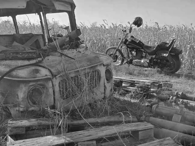 Chopper parked beside a rusted truck in a dry field